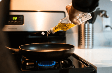 pouring oil in a frying pan on a gas stove